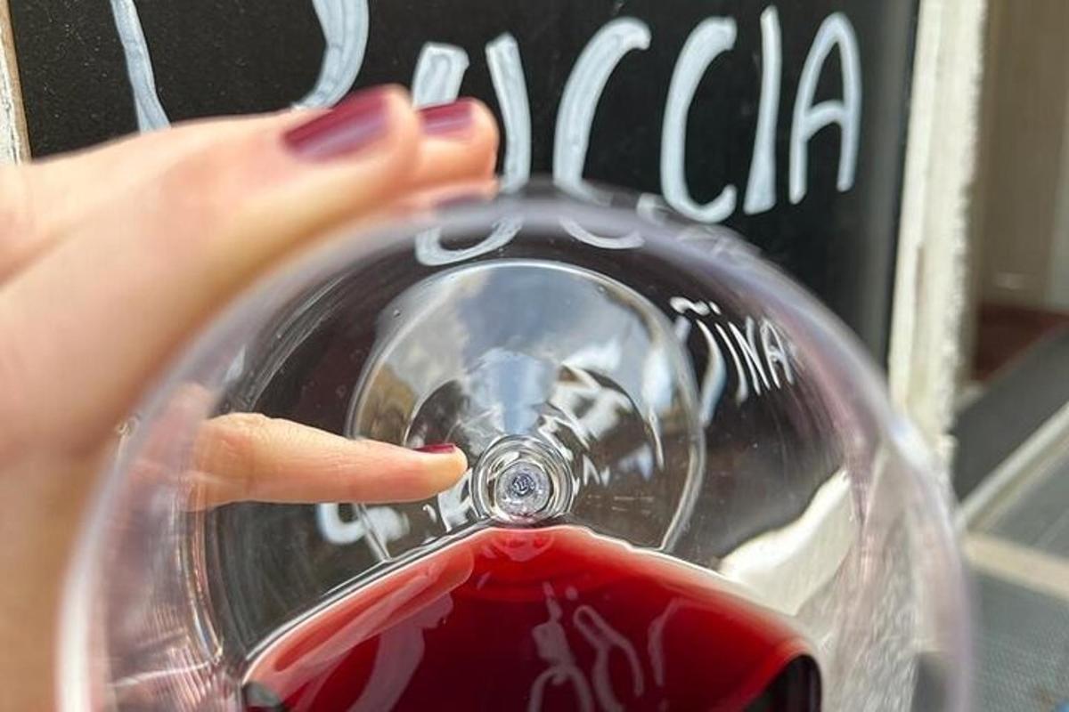 uma mulher está despejando vinho tinto em uma taça