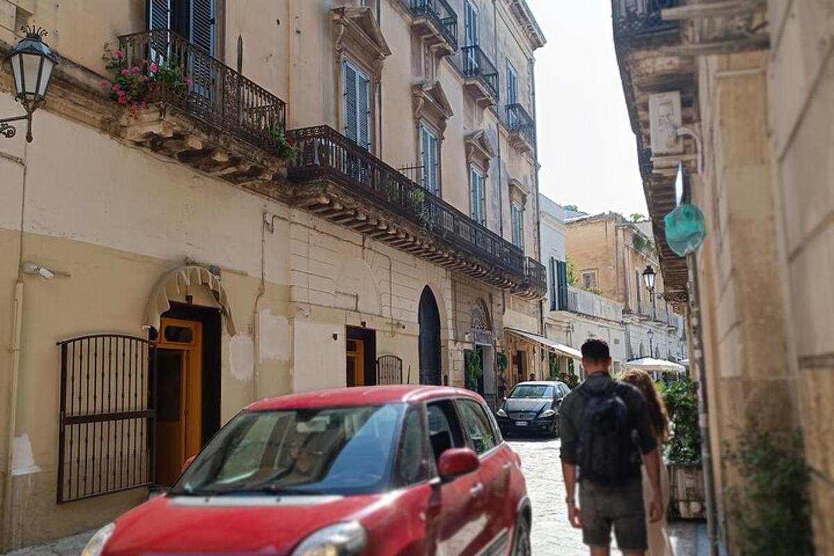 um homem caminhando pela rua ao lado de um carro vermelho