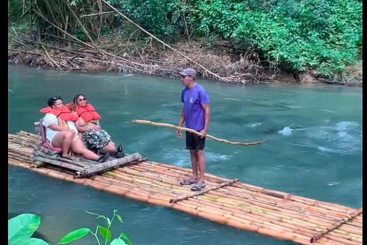 một người đàn ông đứng trên bè tre trên sông