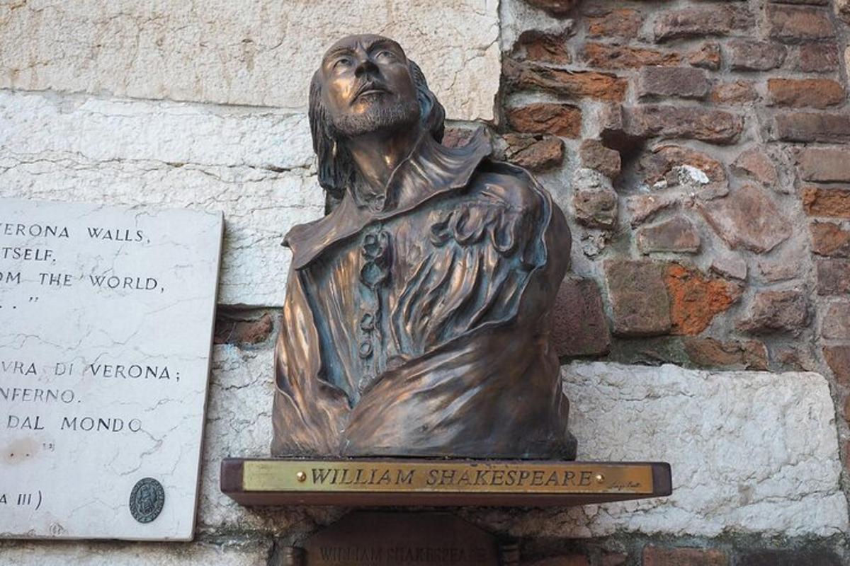 statuja, kurā attēlots vīrietis, kas stāv blakus ēkai