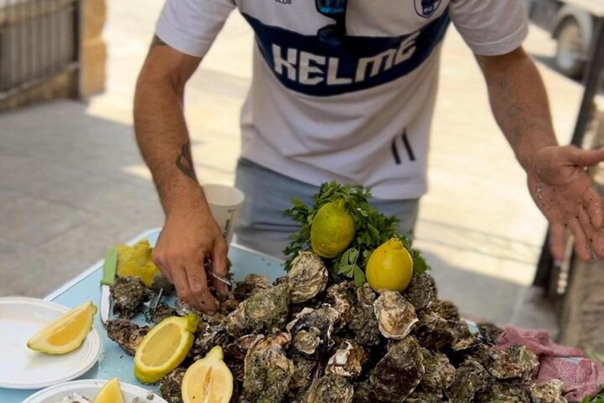 seorang lelaki berdiri di sebelah meja dengan makanan di atasnya
