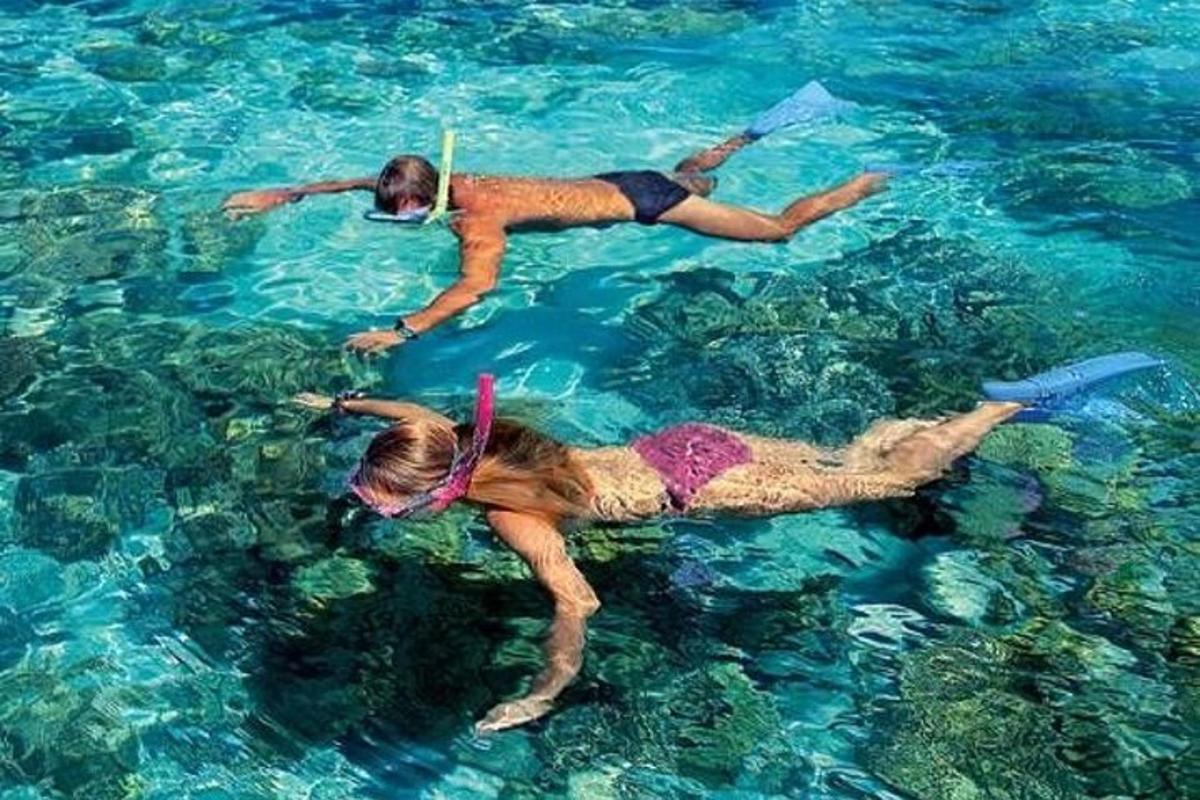 due persone che nuotano nell'acqua azzurra e limpida