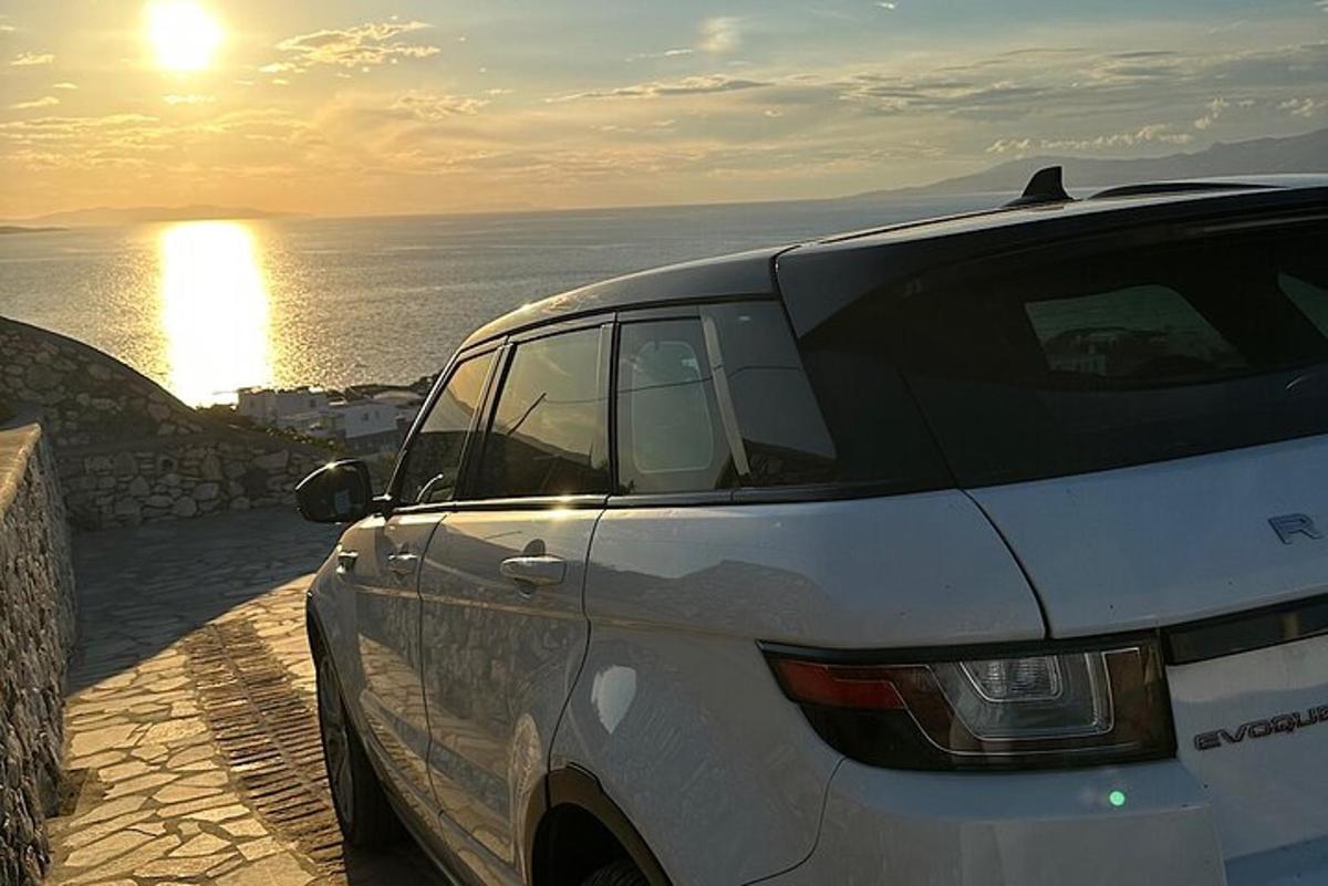 bílé auto zaparkované u oceánu se západem slunce