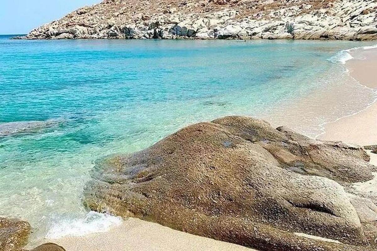 en strand med blåt vand og en stor sten