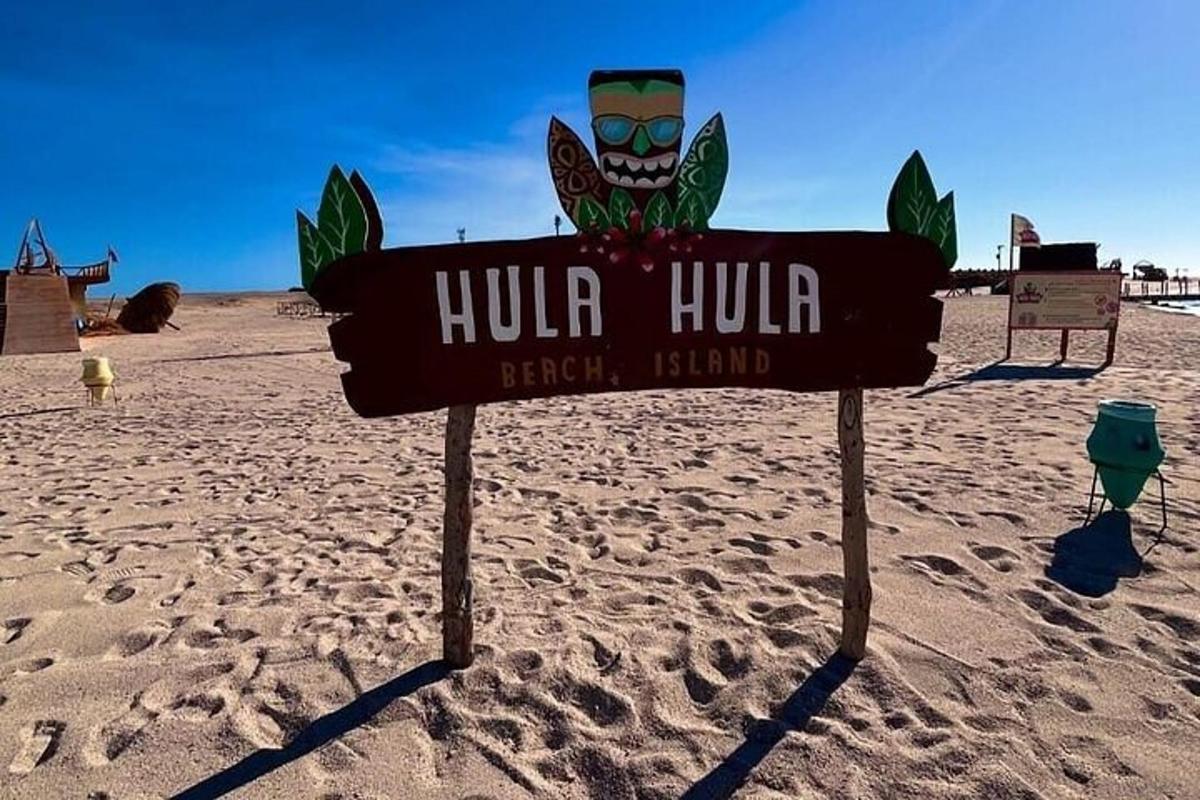 Un cartel que indica una isla de playa Hulum en la arena.