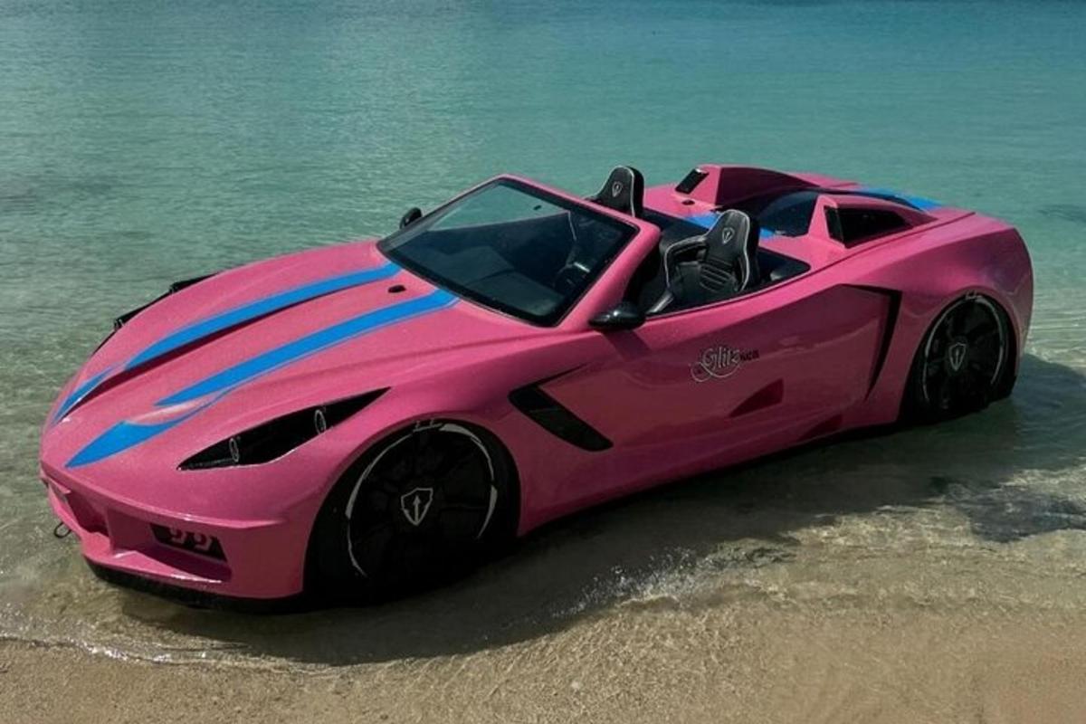 um carro rosa parado na praia perto da água