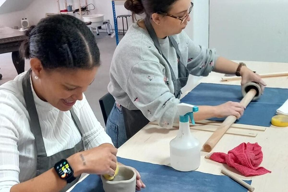 two women sitting at a table working on a piece of wood