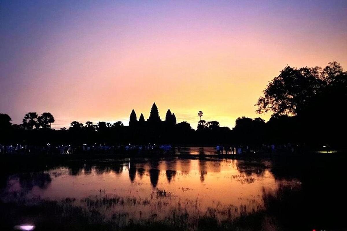 Una puesta de sol sobre un templo con un reflejo en el agua.
