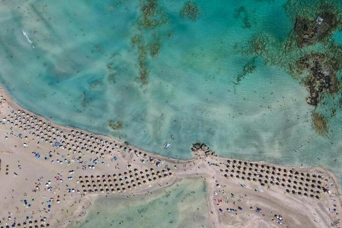 una vista cenital d'una platja amb gent i un far