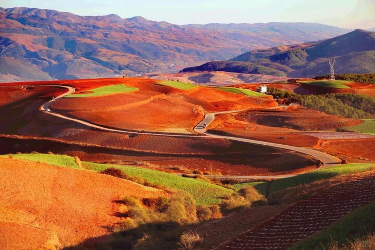 a winding road on a hill with mountains in the background