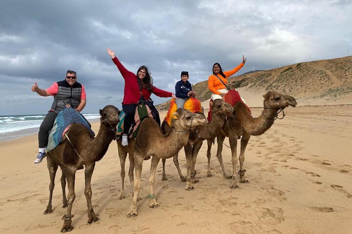 um grupo de pessoas andando de camelo na praia