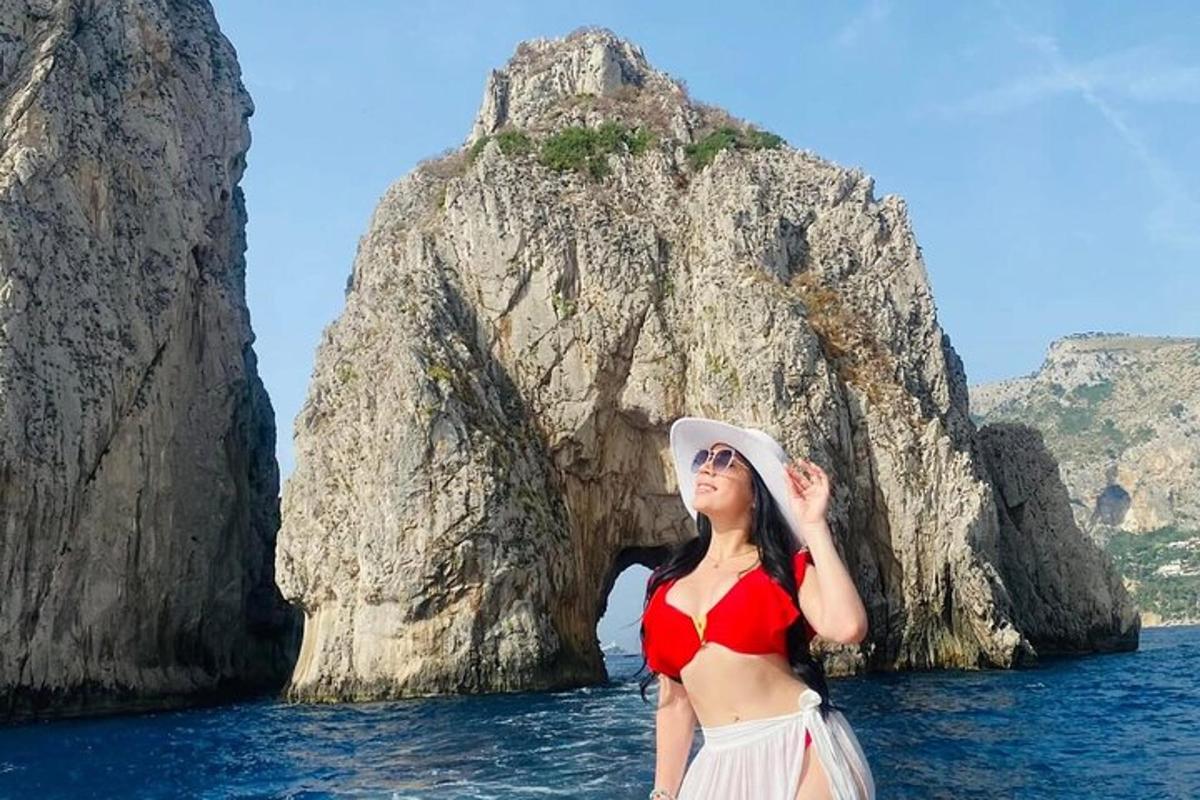 Una mujer parada en el agua frente a una formación rocosa.