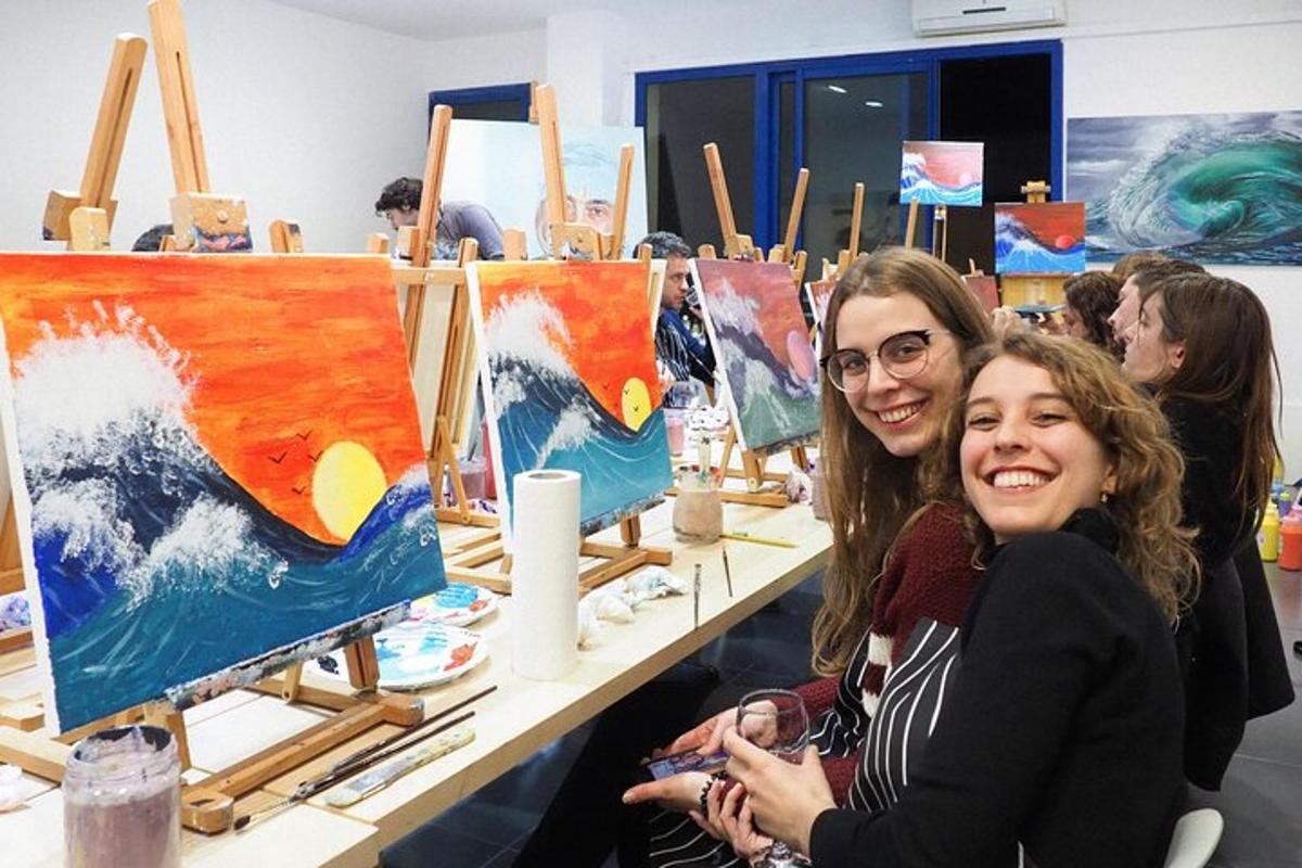 due donne sedute davanti a un tavolo con dei dipinti