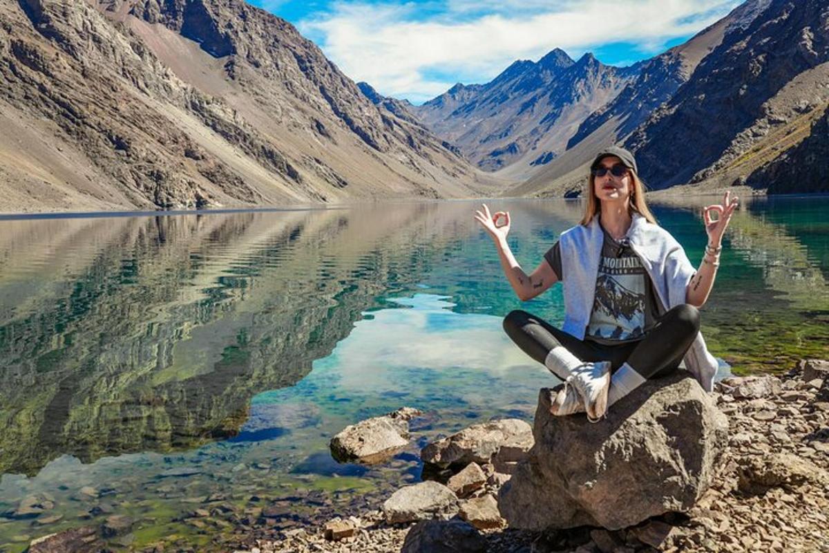 a woman sitting on a rock in front of a lake