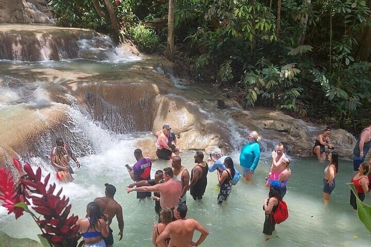eine Gruppe von Menschen im Wasser in der Nähe eines Wasserfalls