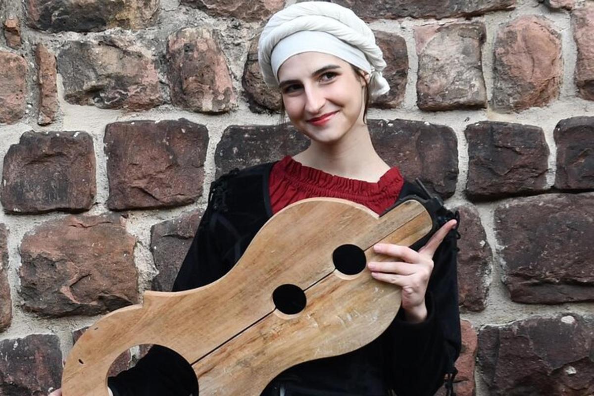 eine Frau mit einer Holzgitarre vor einer Wand