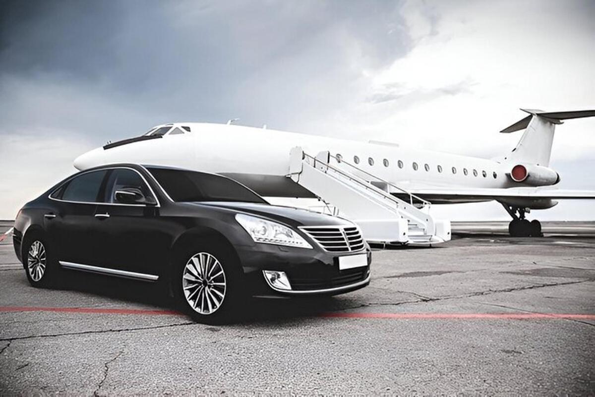 un'auto nera è parcheggiata accanto a un aereo