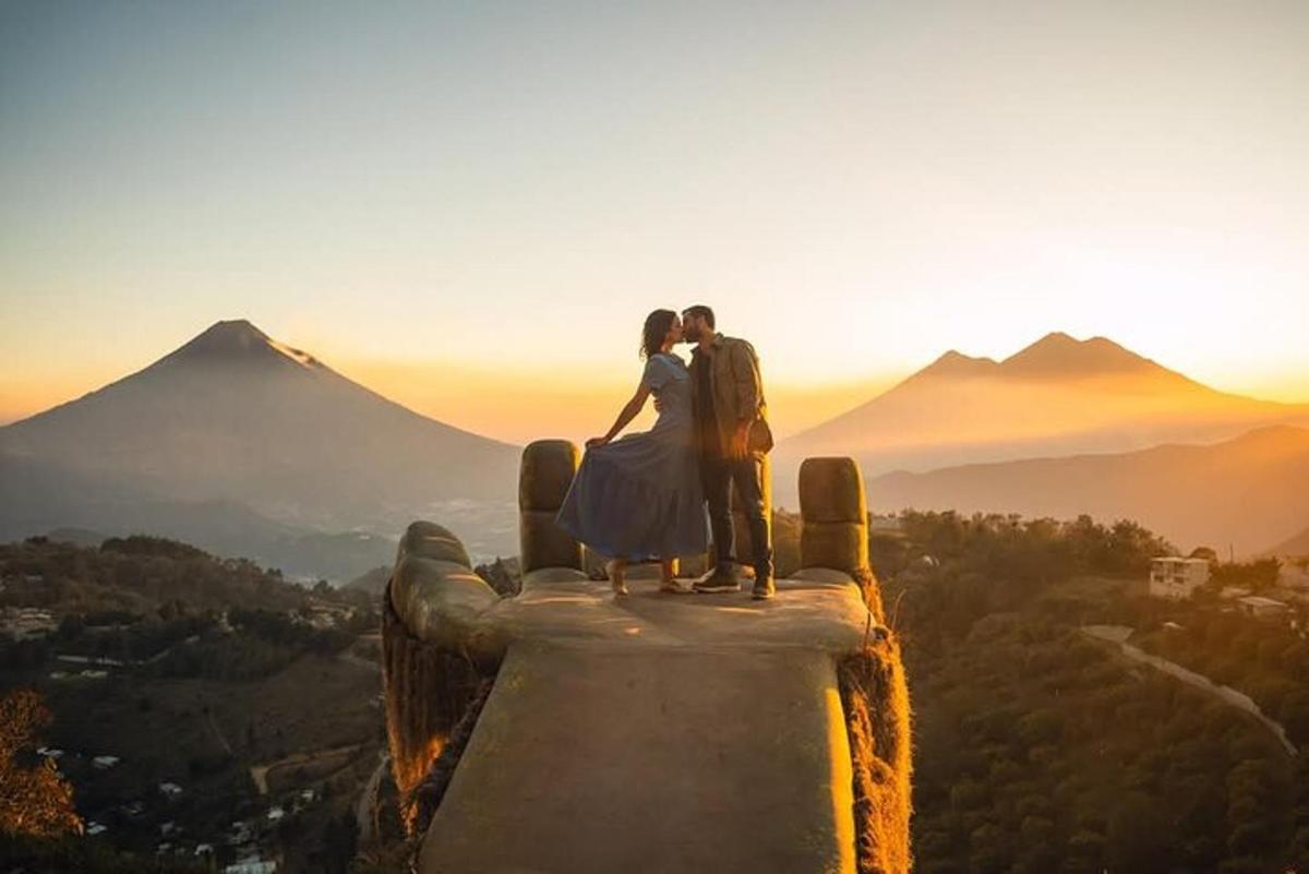a bride and groom standing on the edge of a mountain