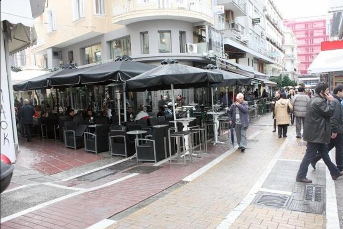 skupina lidí jdoucích po ulici se stoly a slunečníky