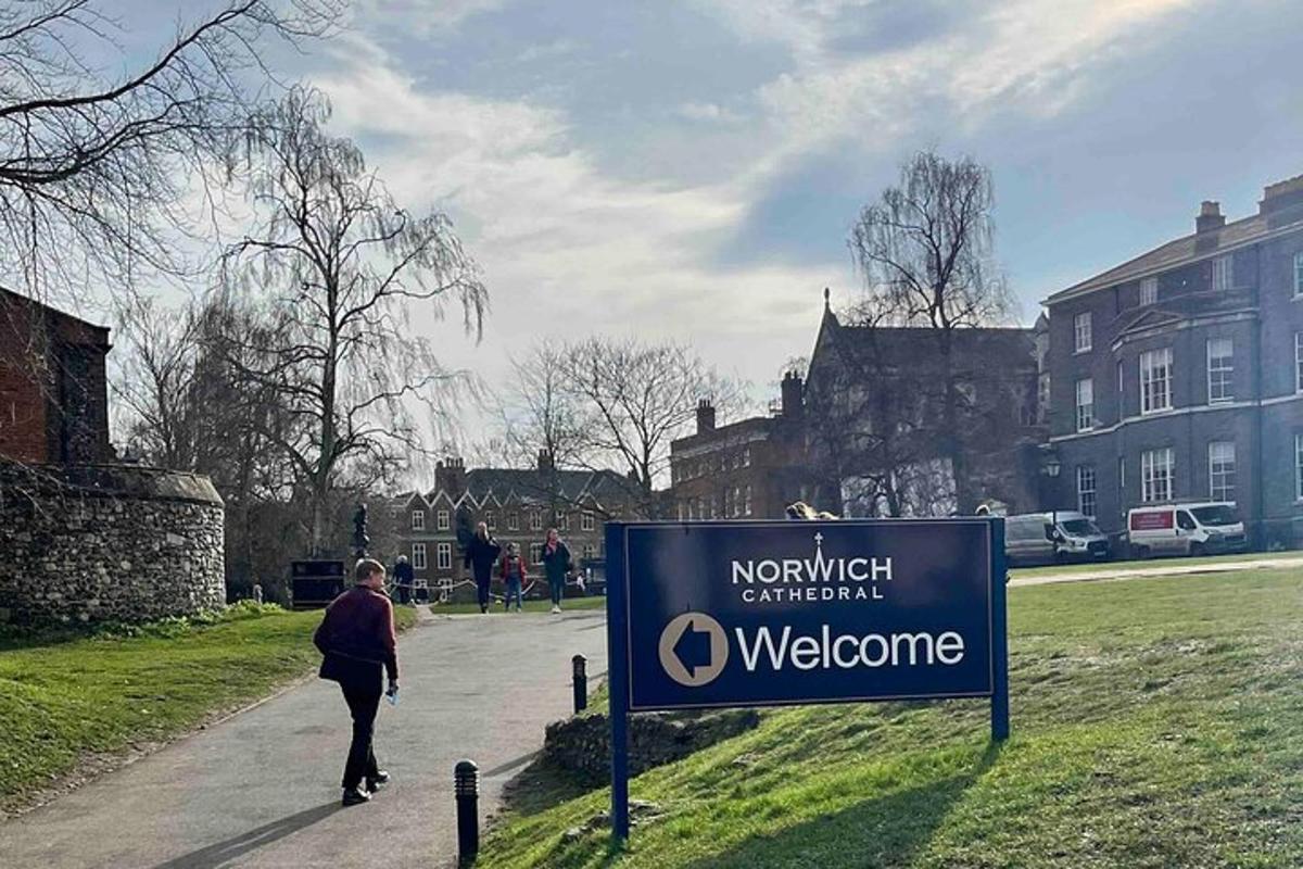 a woman walking down a sidewalk next to a welcome sign
