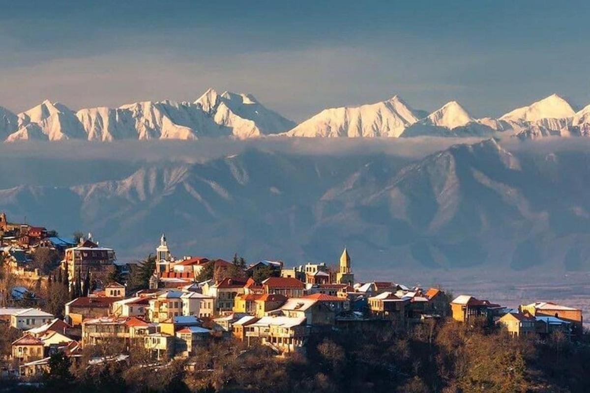 un pueblo en una colina con montañas cubiertas de nieve