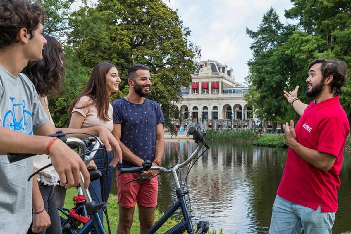 un gruppo di persone in piedi attorno a una bicicletta davanti a uno stagno