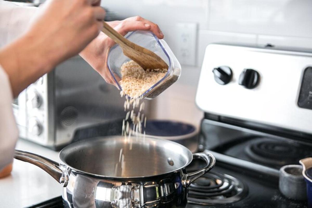 una persona que vierte comida en una olla sobre una estufa
