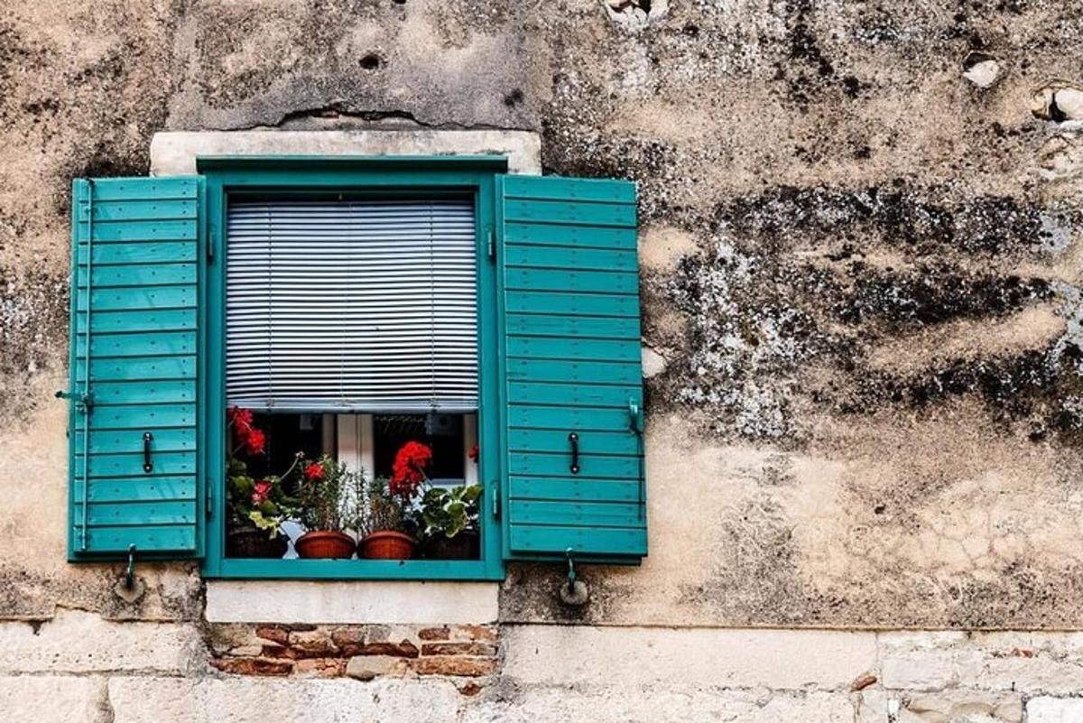 una finestra con persiane blu su un edificio con fiori