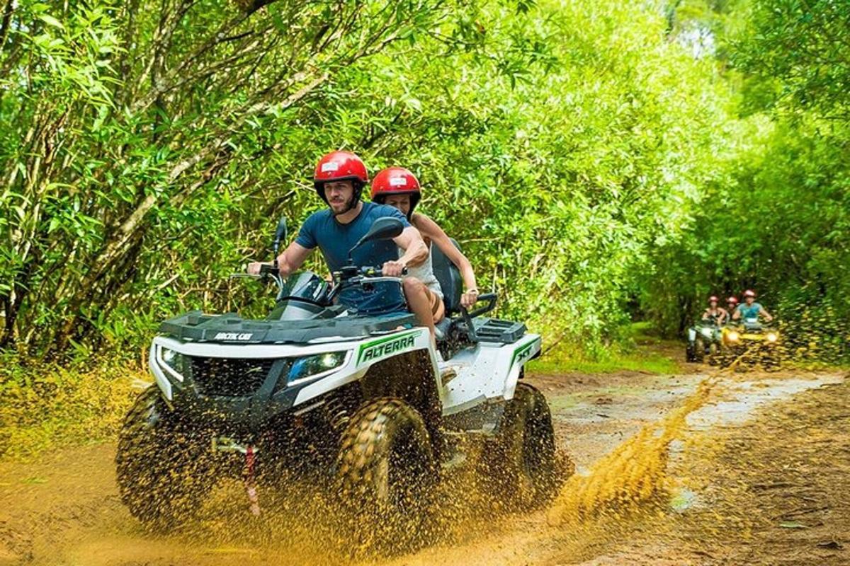 duas pessoas andando em um quadriciclo em uma estrada de terra