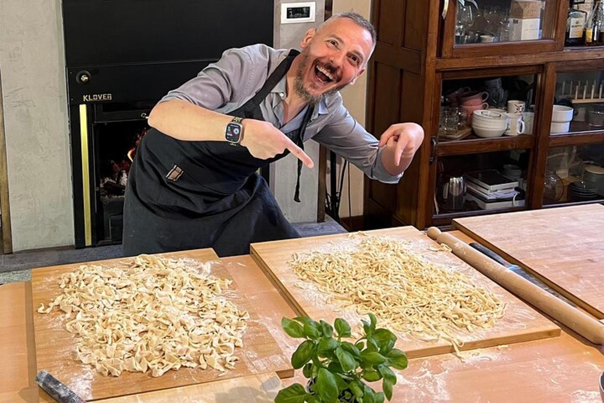 Un hombre con delantal señalando una pila de fideos.