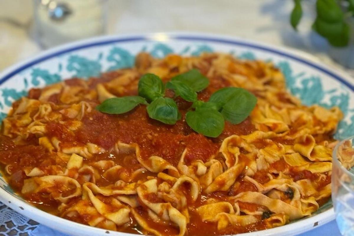 Un tazón de pasta con salsa y verduras encima.