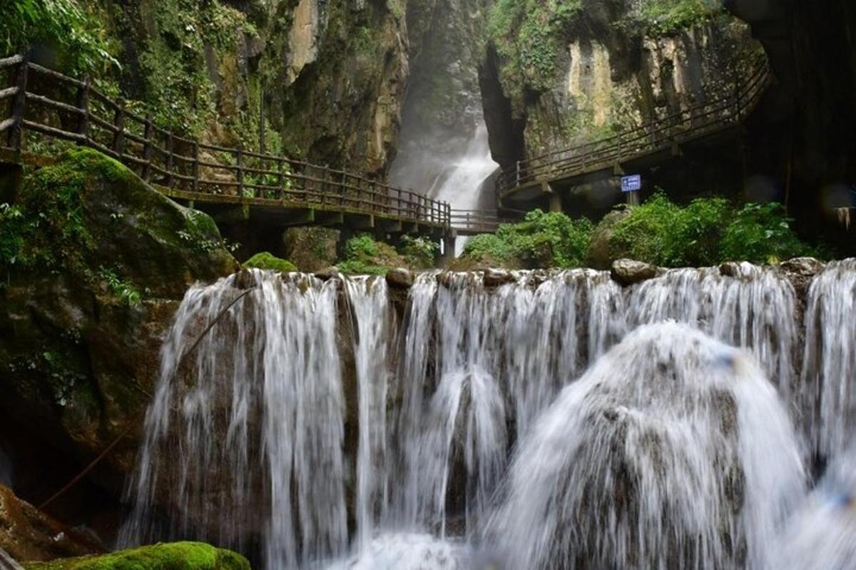 una cascada davant d'una muntanya amb un pont