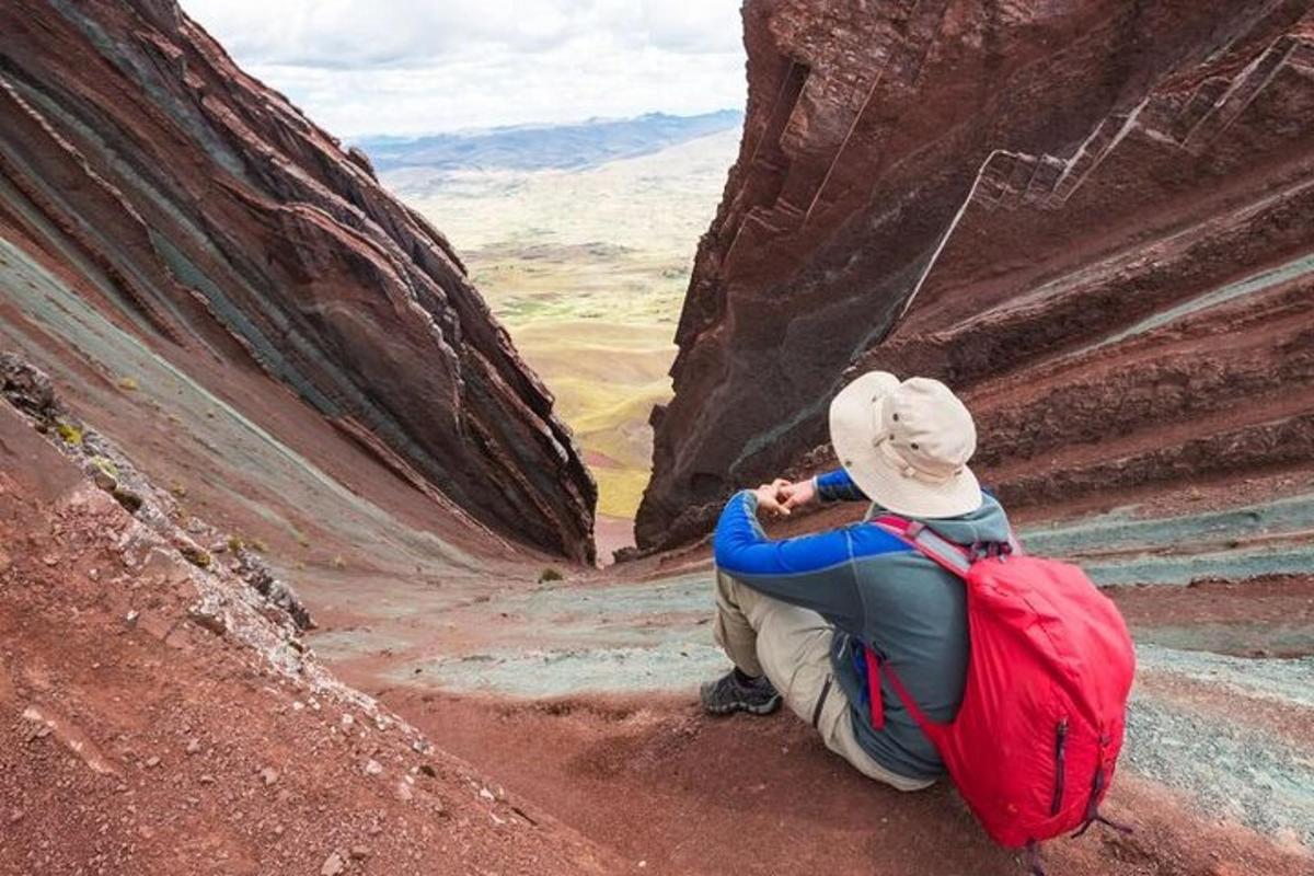 a person sitting on the side of a canyon with a backpack