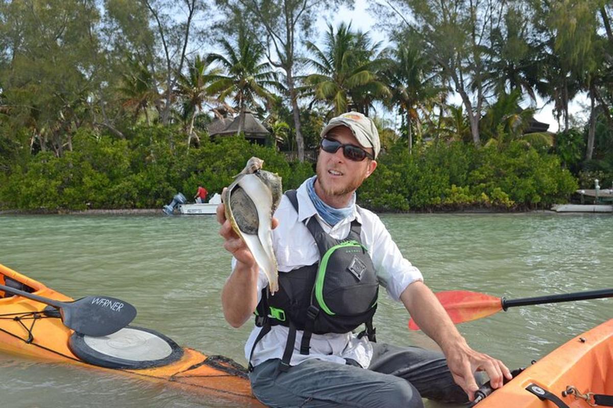 một người đàn ông ngồi trên thuyền kayak cầm mái chèo