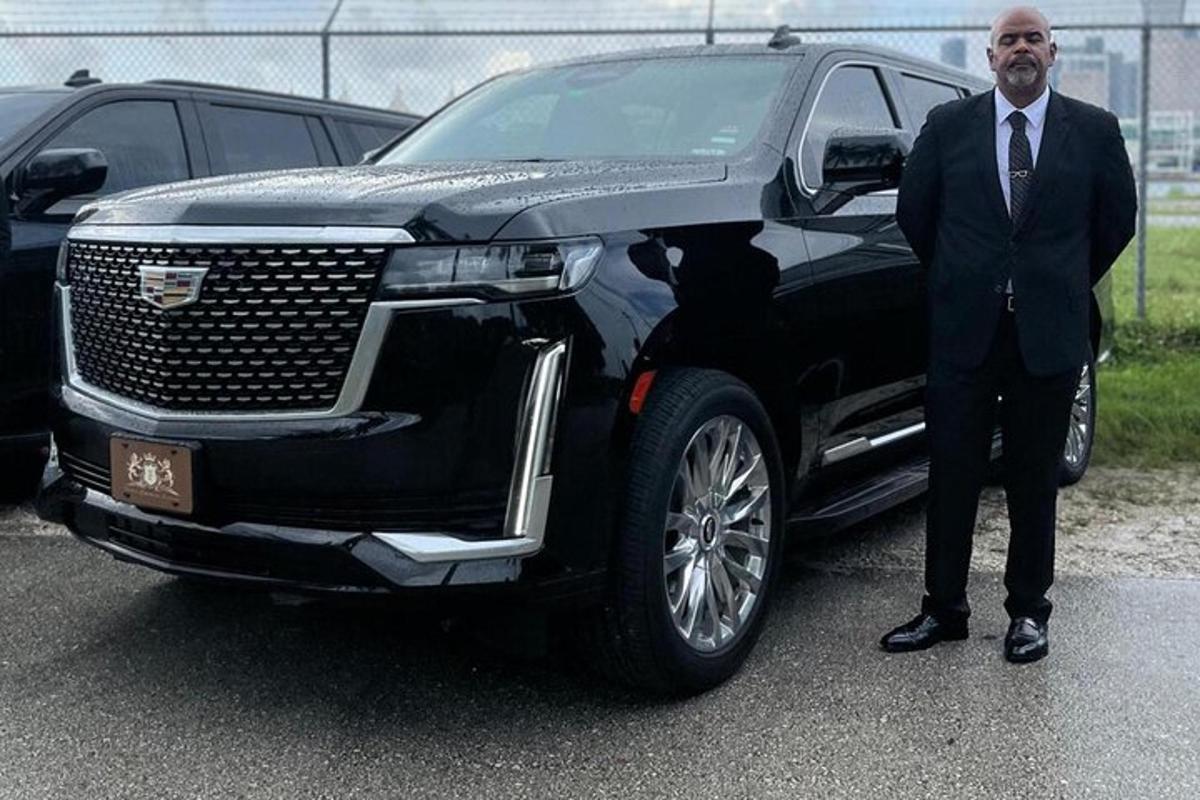 en man i kostym som står bredvid en svart limousine