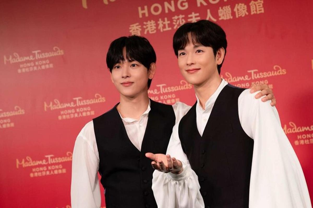 two young men standing in front of a red wall