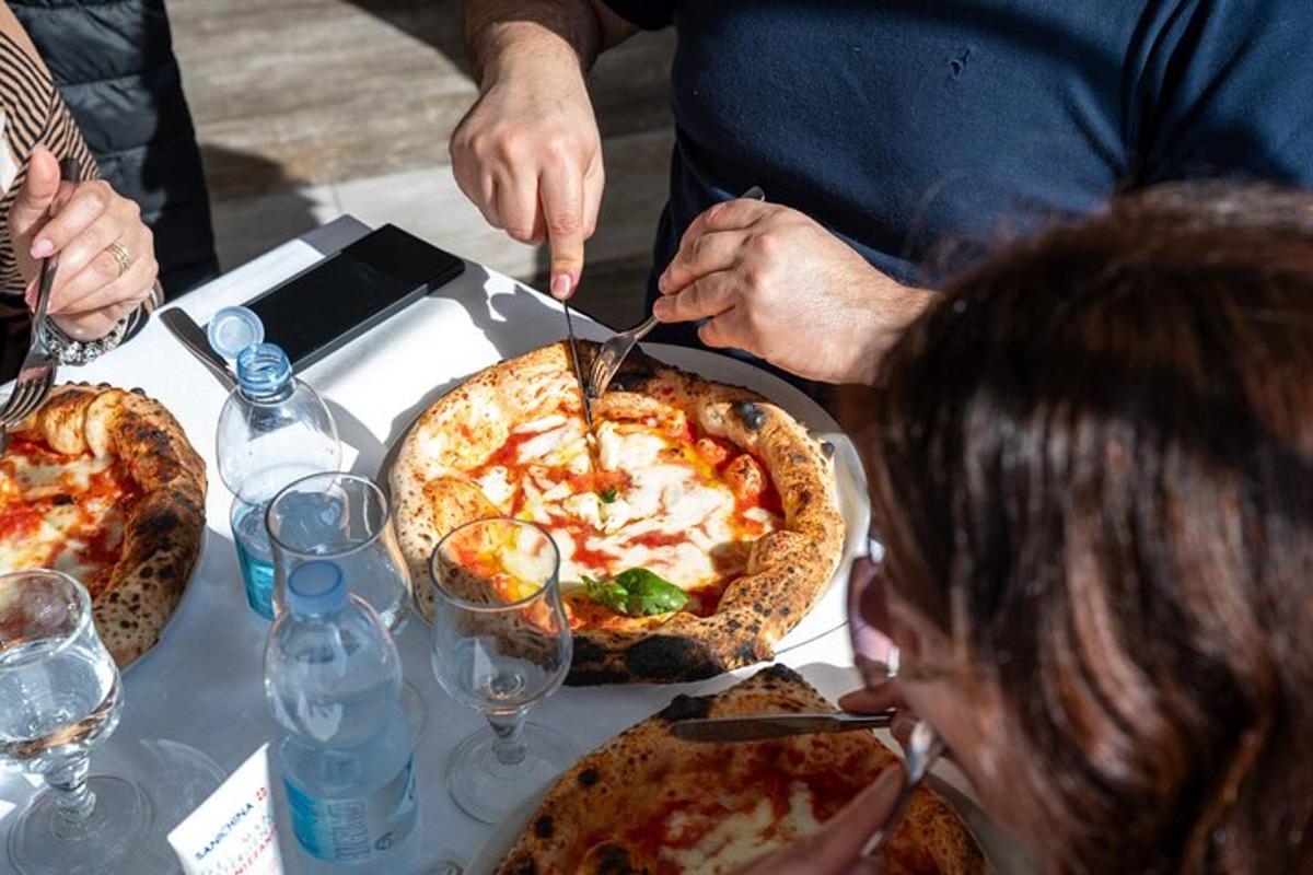 Bir kişi masanın üzerinde pizza kesiyor