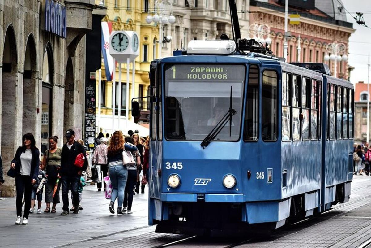 Modrá tramvaj na městské ulici s jdoucími lidmi