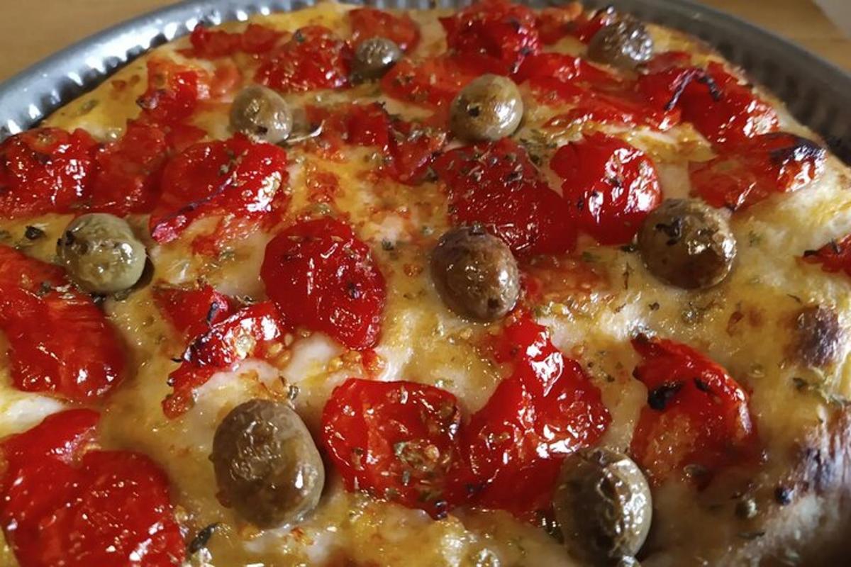 một chiếc bánh pizza với pepperoni và ô liu trên chảo