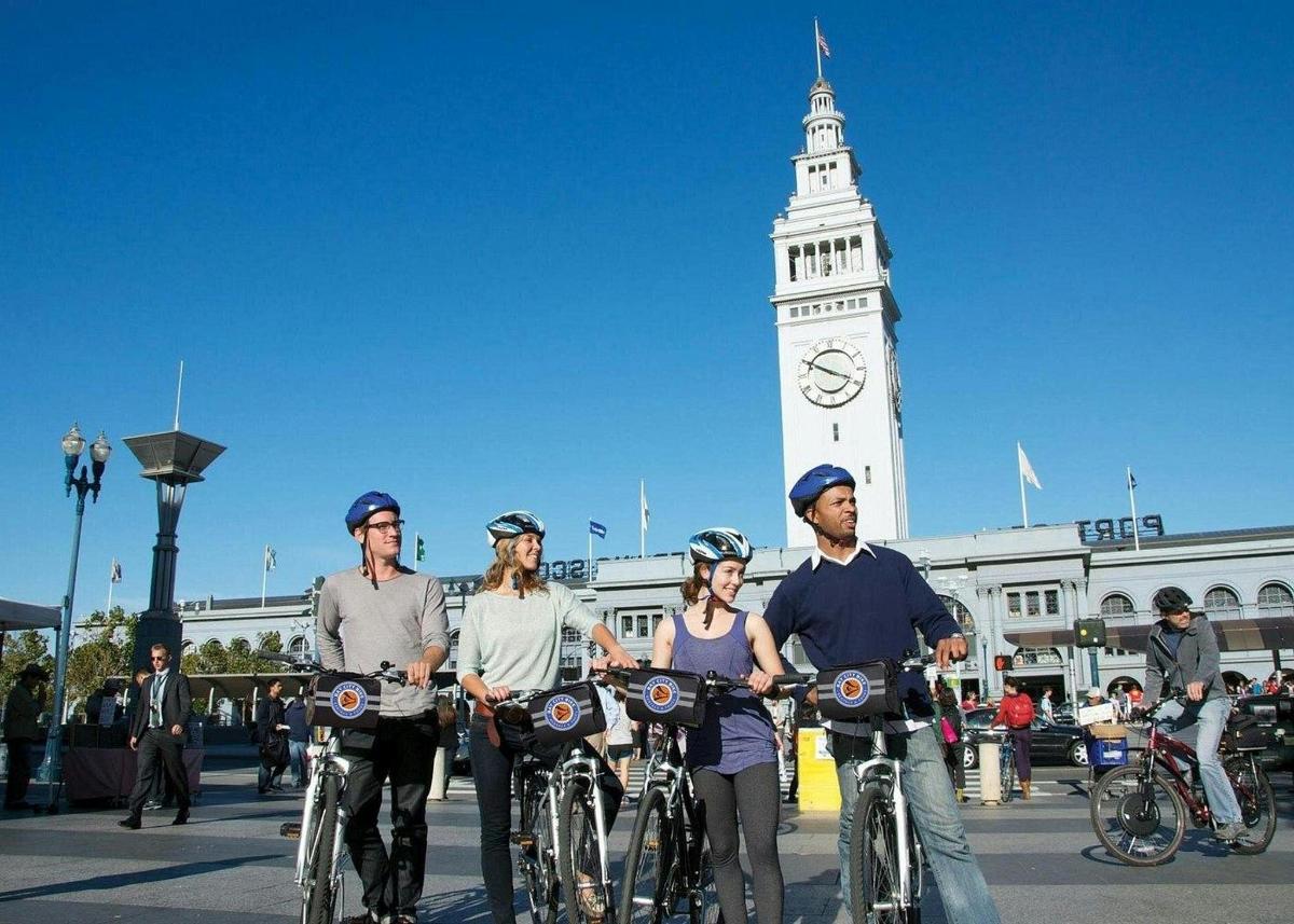 Un grupo de personas en bicicleta frente a una torre de reloj.