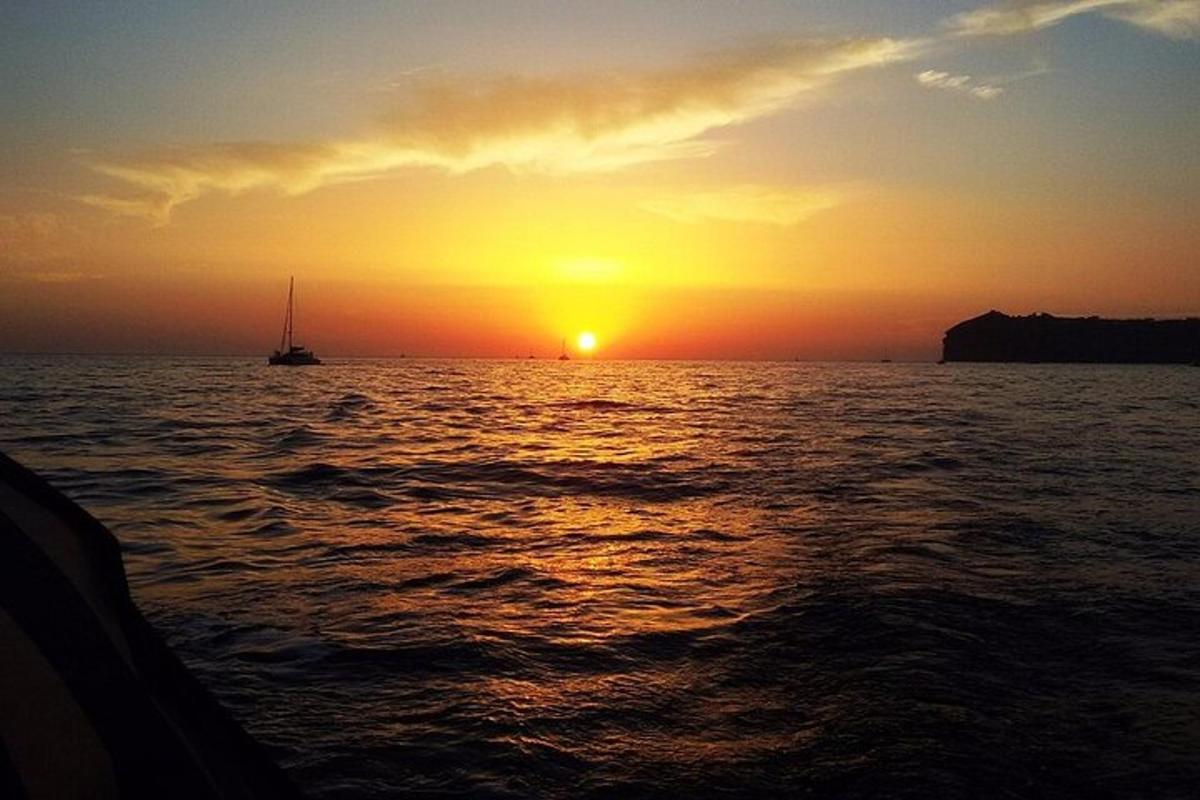 sončni zahod na oceanu s čolnom v vodi