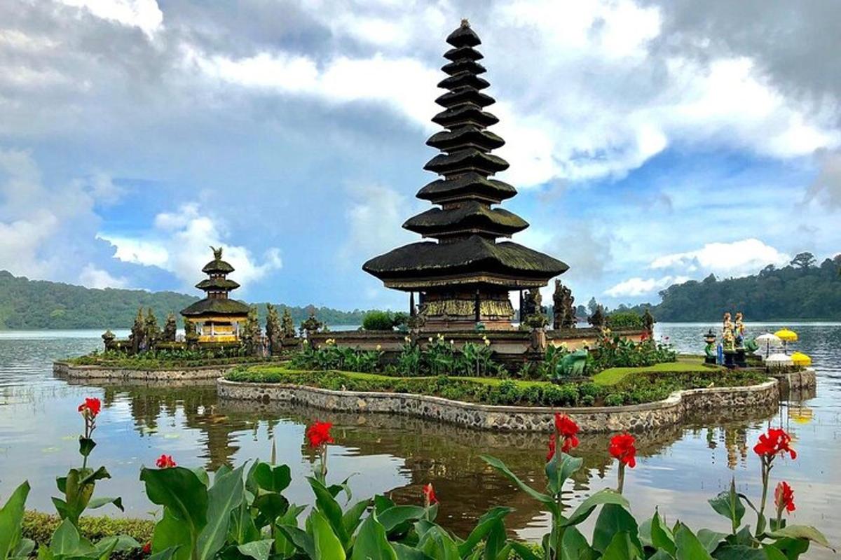 una pagoda in mezzo a un lago con fiori rossi