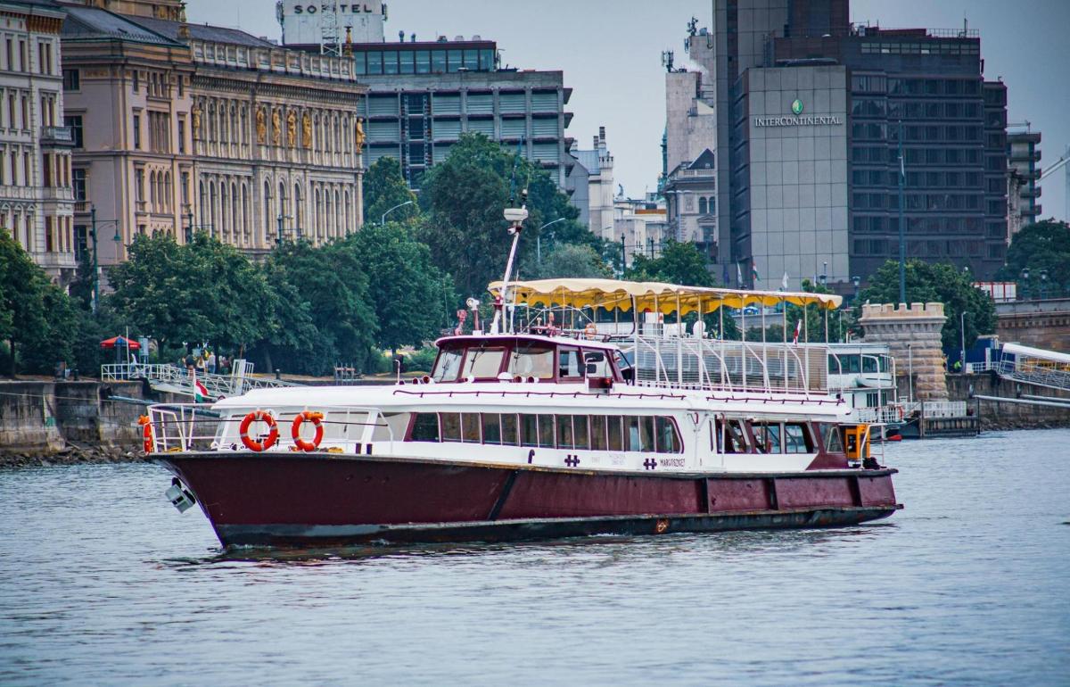 a red and white boat on a river with buildings