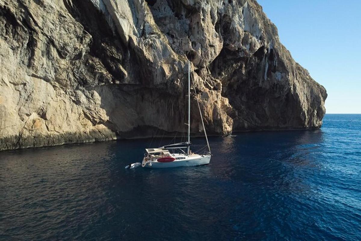 μια βάρκα στο νερό δίπλα σε έναν απότομο βράχο