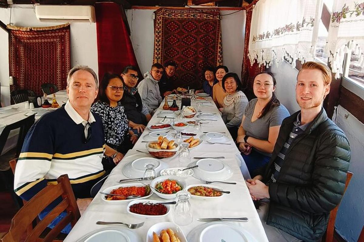 a group of people sitting at a long table with food