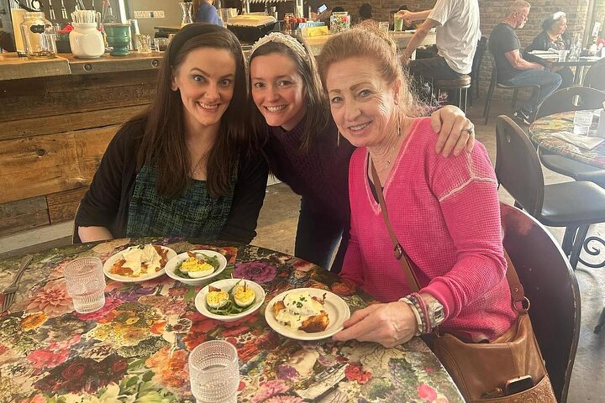 three women sitting at a table with plates of food