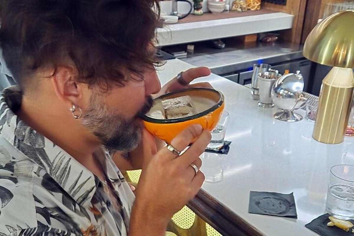 Ένας άντρας πίνει ένα ποτήρι πορτοκαλί υγρό