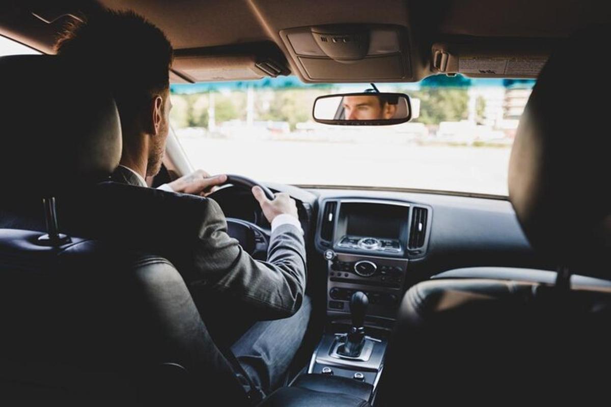 seorang lelaki yang duduk di dalam kereta melihat telefon bimbitnya