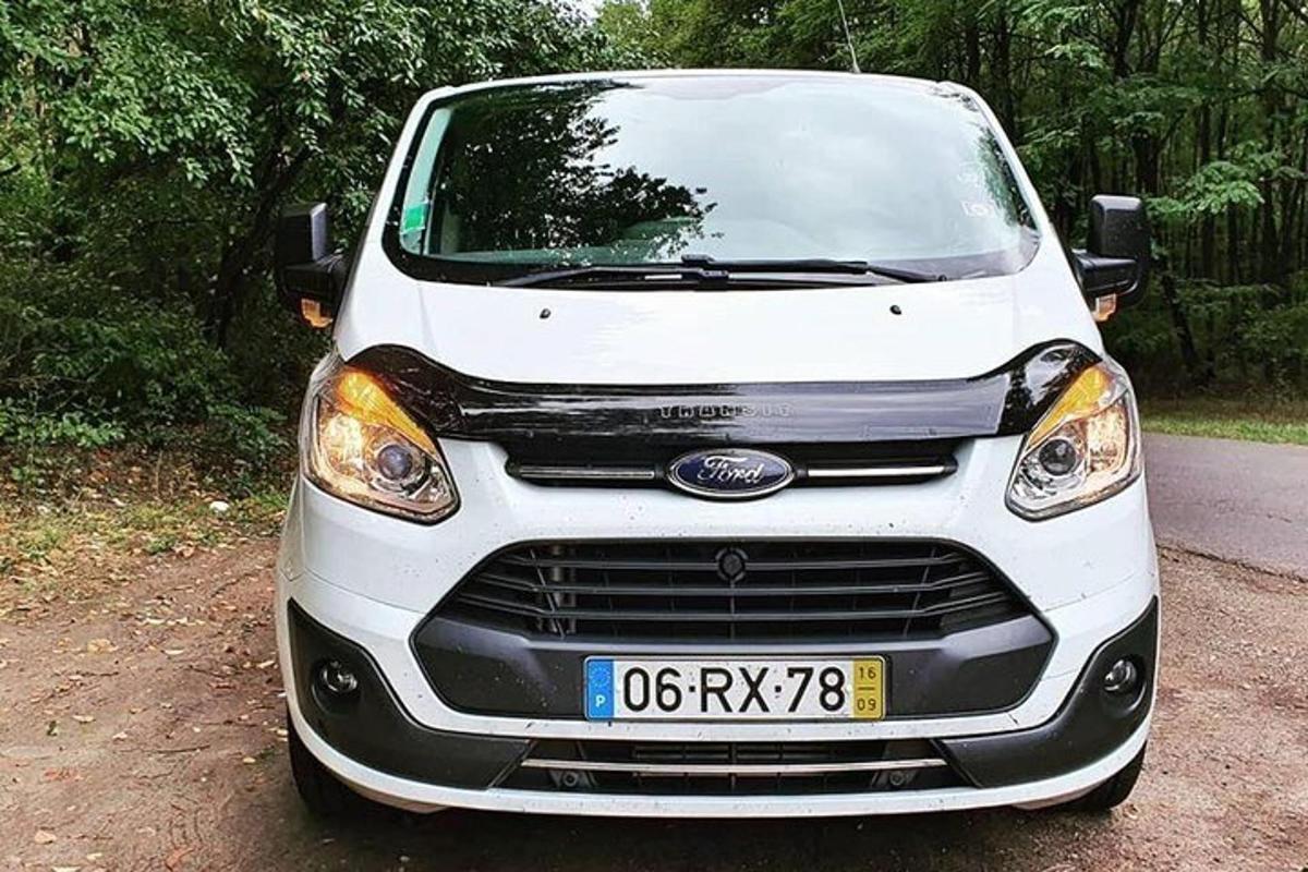 en hvit bil parkert på en grusvei