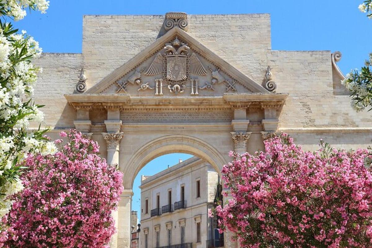 an arch with pink flowers in front of a building